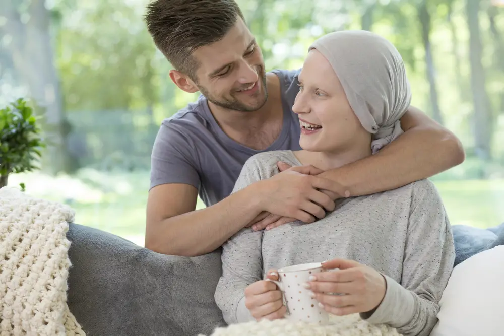 cancer patients and her partner hugging her on a sofa