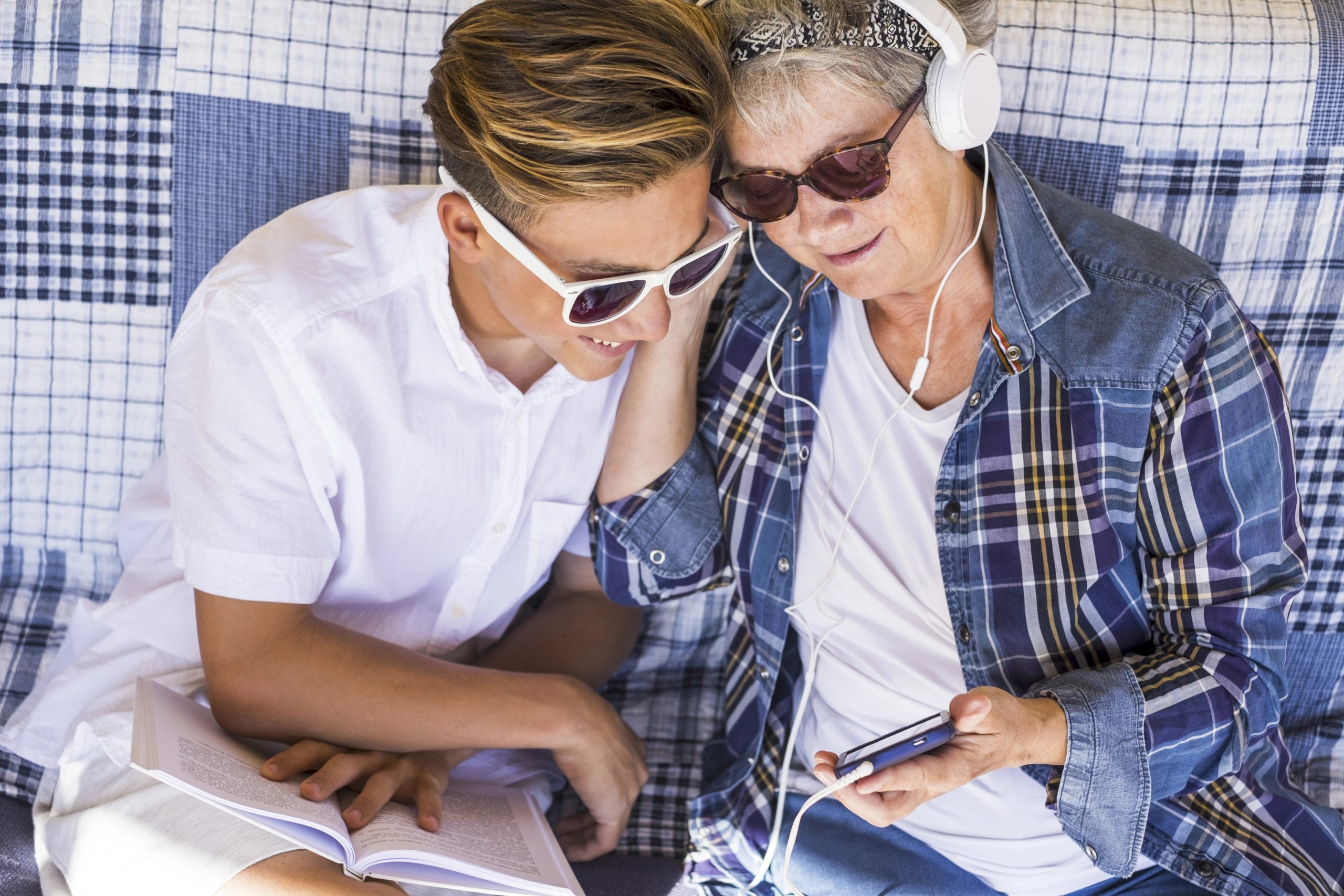 Couple young and old grandmother and teenager grandson family time together listen music with headphones and enjoy the day