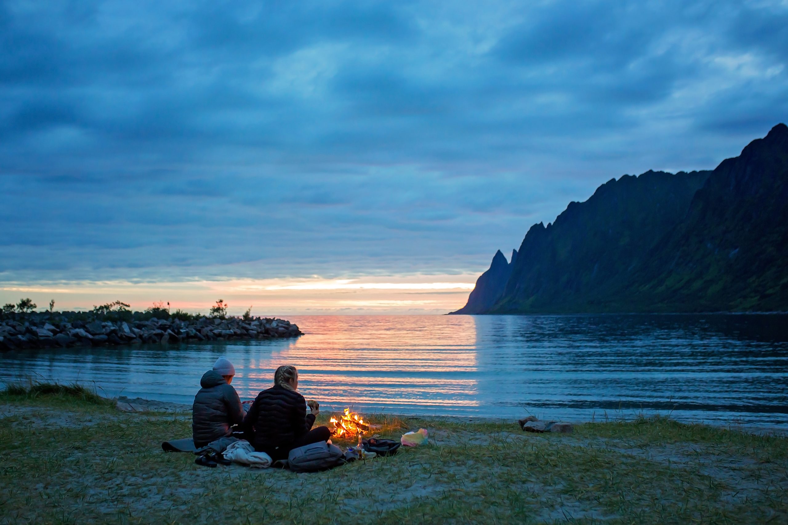 People, enjoying fireplace on the beach, wild camping on Ersfjord beach in Senja national park in northern Norway, summertime