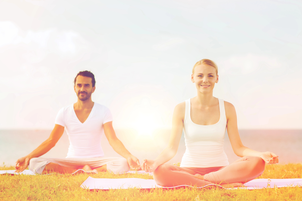 Smiling couple making yoga exercises outdoors
